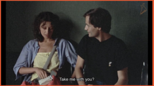 برشی از فیلم The Green Ray | زن و مرد در کنار یکدیگر در ترمینال نشسته‌اند و زن از مرد می‌پرسد: «مرا همراه می‌بری؟»