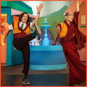 صحنه‌ای از سریال کیدینگ، جف پیکلز و دالایی لاما در نمایش کودکانه‌ای در حال رقصند.